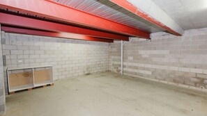 Ein Zimmer mit weißen Ziegelwänden, einem Betonboden und einer roten Decke.