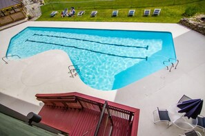 Ein Swimmingpool mit roter Liegefläche und Liegestühlen.