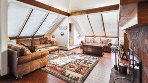 Un salón tipo loft con techos altos, vigas de madera a la vista y ventanas grandes.