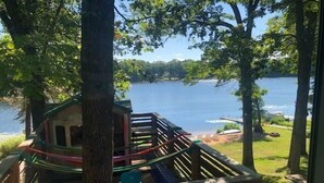 Blick auf einen See mit einer Holzterrasse und einem kleinen Spielhaus.