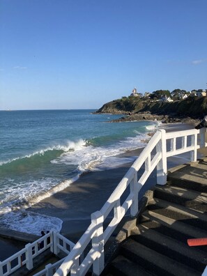 Una escalera costera que lleva a una playa con olas rompiendo en la orilla.