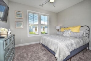 A bedroom with a bed, dresser, and two windows.