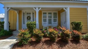 A yellow house with a porch, white columns, and a door with a wreath. - 5105 The Retreat - Barefoot Resort Rentals (North Myrtle Beach)