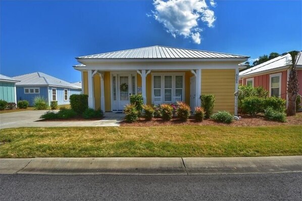 A single-story house with a yellow facade, white trim, and a porch with white railings.