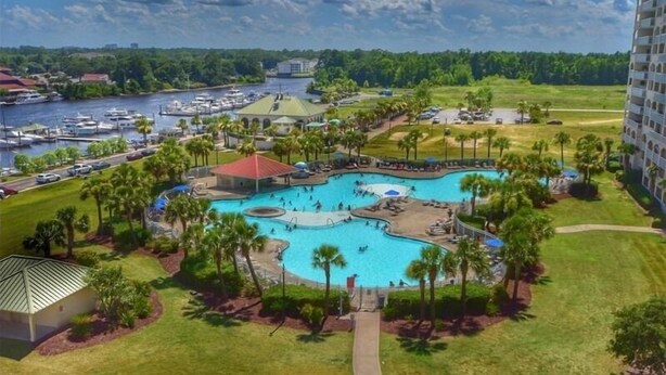 A resort with a large central pool, a marina with boats, and a lush green landscape. - 5105 The Retreat - Barefoot Resort Rentals (North Myrtle Beach)