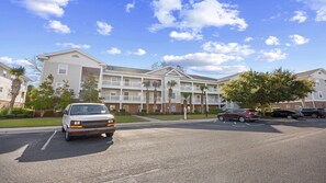 A multi-story apartment building with a parking lot in front.