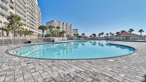 Une piscine dotée d’une terrasse dallée, entourée de palmiers et d’une clôture blanche.