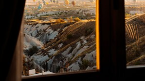 Une vue sur un paysage, visible depuis une fenêtre, où l’on peut admirer de nombreux ballons à air chaud.