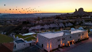 Un bâtiment historique en pierre, doté d’un toit plat, entouré d’un jardin bien entretenu et d’une piscine.