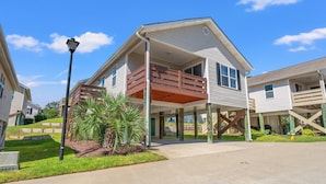 A two-story house with a balcony, a covered porch, and a well-maintained lawn. - Spacious cottage close to the beach with an outdoor pool.  OGC 9632 (Myrtle Beach)