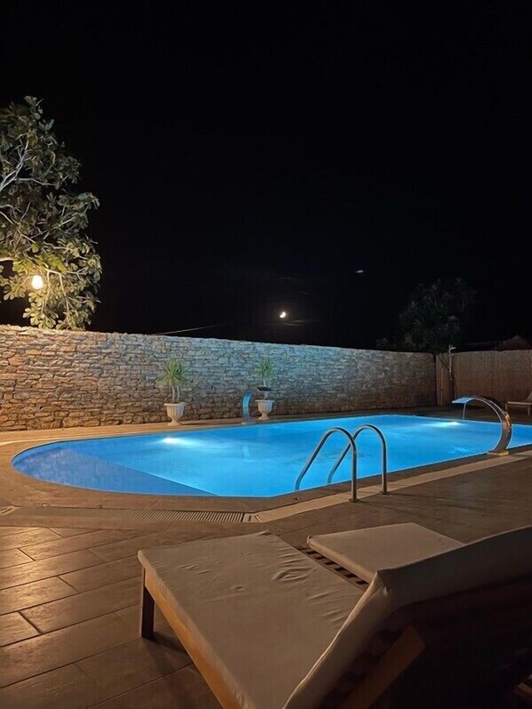 A swimming pool with a stone wall, lounge chairs, and potted plants. - ALBIZIA BOUTIQUE HOTEL (Ula)