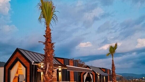 A modern house with a large deck, a small attached cabin, and a palm tree in the foreground. - ALBIZIA BOUTIQUE HOTEL (Ula)