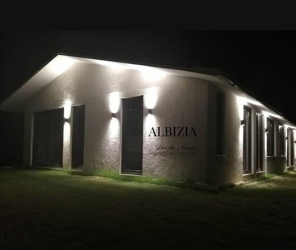 A building with the name "ALBIZIA" illuminated at night, featuring a simple, modern architectural style with a flat roof and minimalistic design. - ALBIZIA BOUTIQUE HOTEL (Ula)