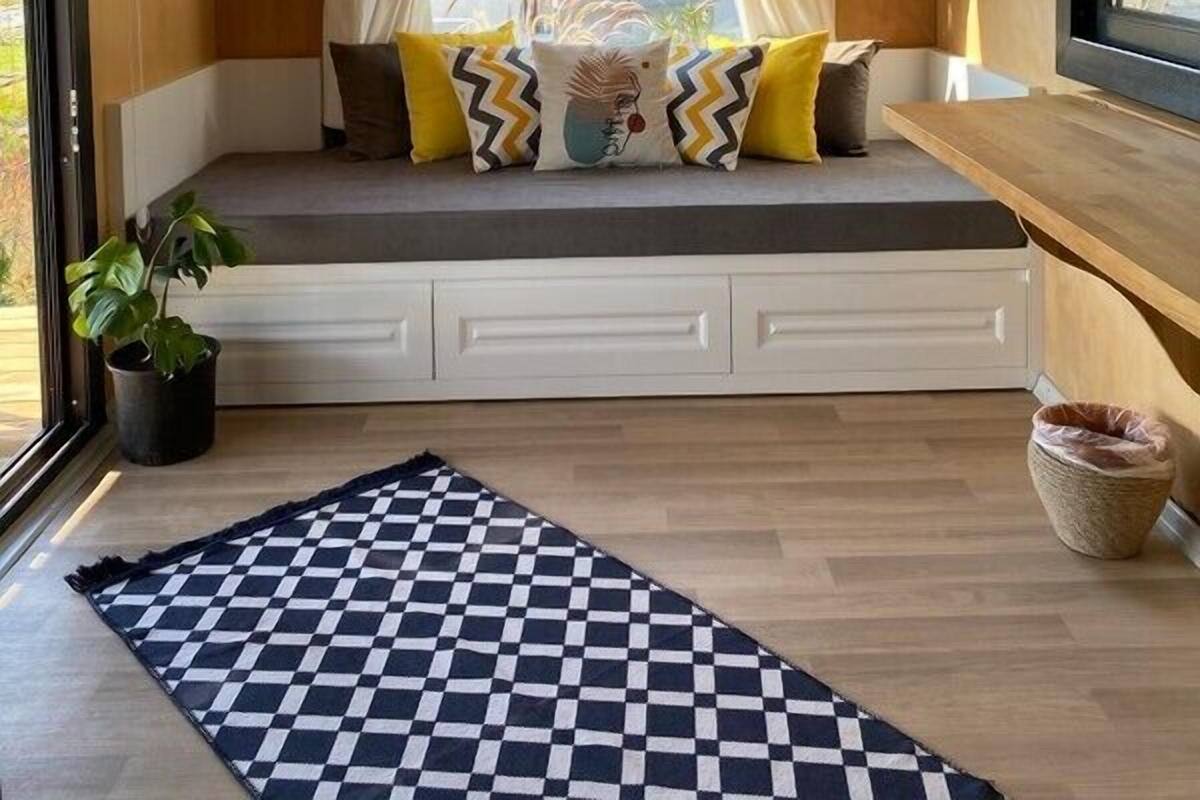 A cozy room with a built-in bench, a checkered rug, and a potted plant.