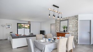 A modern living room with a dining area, a stone accent wall, and a large mirror.