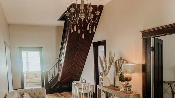 A spacious living room with a high ceiling, a chandelier, a staircase, a dining area, and a cozy seating area. - The Yellow House - Hidden Gem in heart of Portland (Portland)