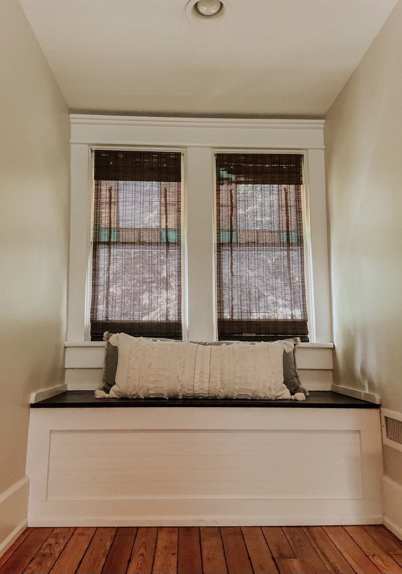A room with a built-in bench under a window with blinds.