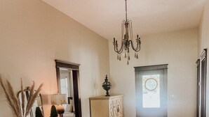 A living room with a wooden floor, a white sofa, a chandelier, and a cabinet with drawers. - The Yellow House - Hidden Gem in heart of Portland (Portland)