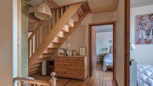 A wooden staircase leading to a bedroom with a bed and a dresser.