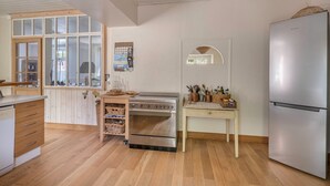 A kitchen with wooden cabinets, a stainless steel oven, a refrigerator, and a window with a view of the outdoors.
