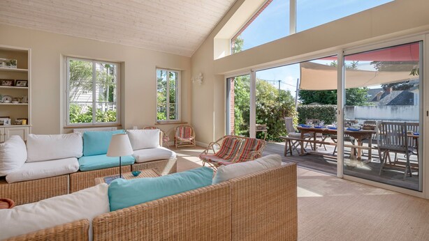 A spacious living area with wicker furniture, a sofa set, and a dining table with chairs.
