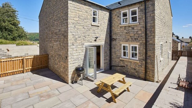 A stone house with a patio, a barbecue, and a wooden table. - Host & Stay | Foggyshaw Lodge (Middlesmoor)