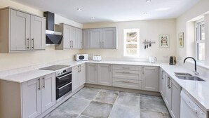 A modern kitchen with grey cabinets, a built-in oven, a microwave, and a dishwasher. - Host & Stay | Foggyshaw Lodge (Middlesmoor)