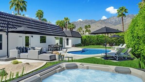 Een modern huis met een zwembad, terras en een jacuzzi.