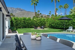A poolside area with a table, chairs, and potted plants.