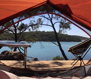 A tent with a table and chair set up near a lake, surrounded by trees. - Kratos Glamping (Ayvalik)