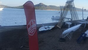 Ein Strandabschnitt mit einer roten Flagge, einem weißen Boot und einer Wasserrutschen-Konstruktion.