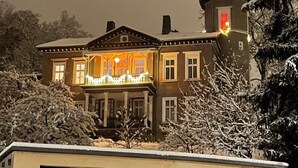 Ein zweistöckiges Gebäude mit Balkon und einem turmartigen Anbau auf der rechten Seite.