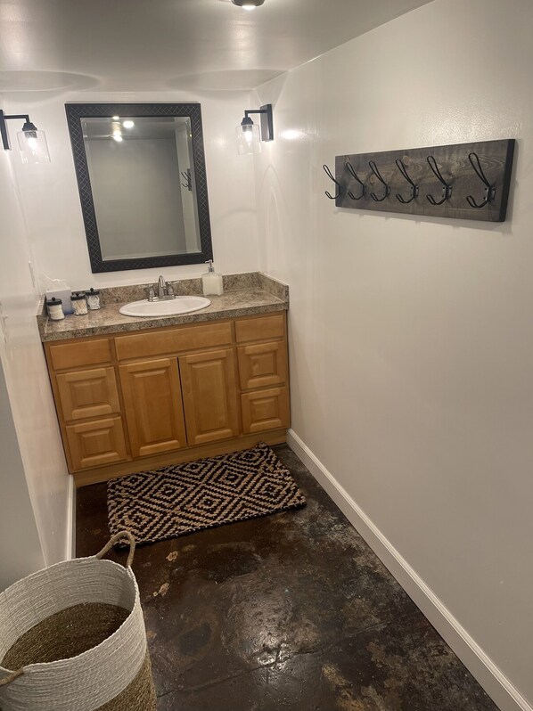 A bathroom with a sink, mirror, wooden cabinets, and a rug on the floor.