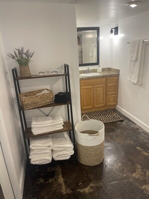 A bathroom with a wooden vanity, a sink, a mirror, and a towel rack. - Cozy 2 Bed (Sterling)