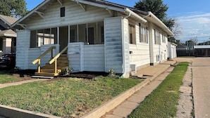 A single-story house with a front porch, a staircase leading to the entrance, and a number '116' on the front. - Cozy 2 Bed (Sterling)