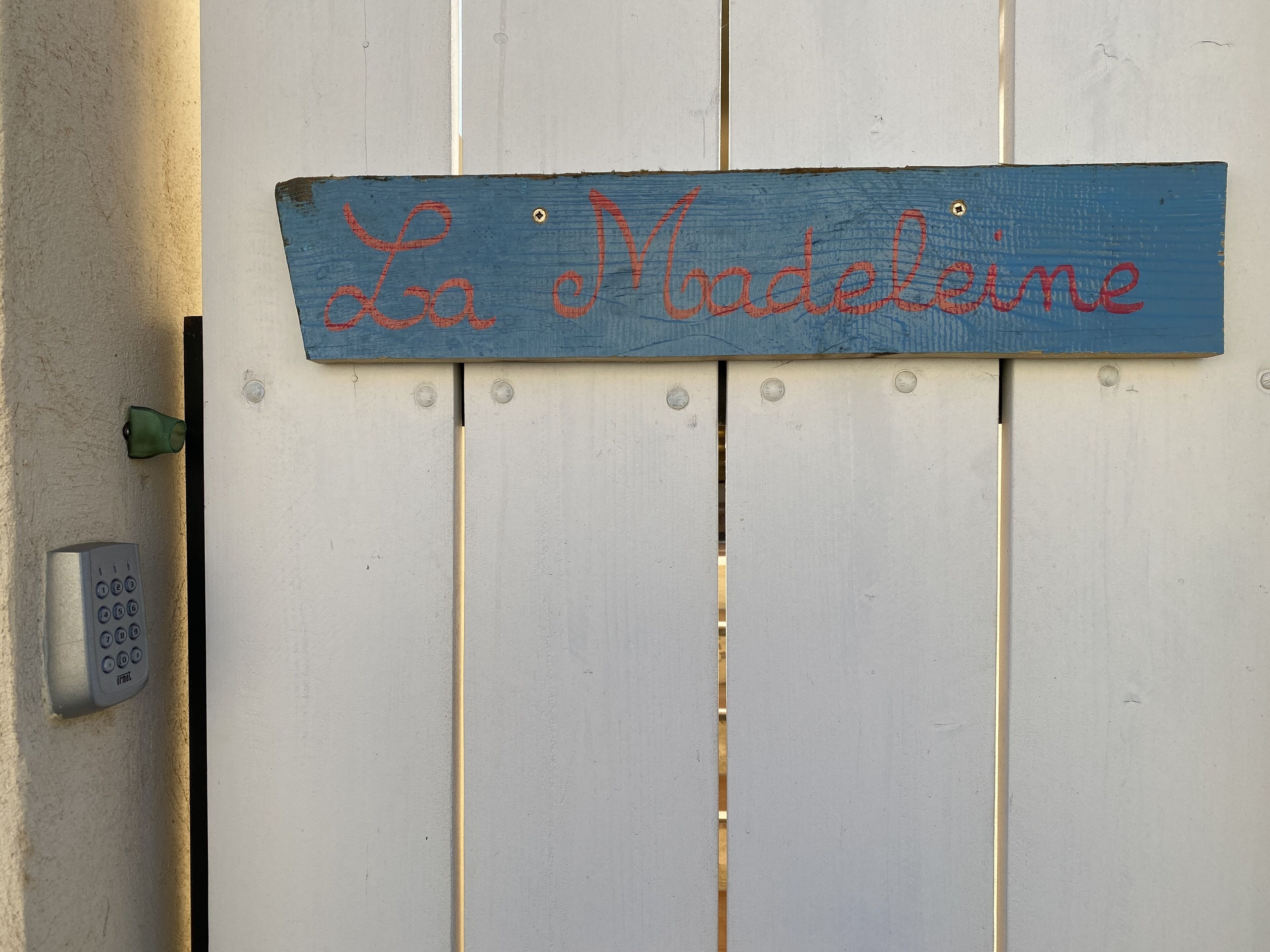 Une enseigne bleue avec le nom «La Madeleine» écrit en lettres rouges sur une porte blanche.