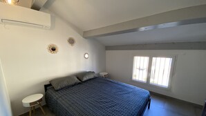 Een slaapkamer met een bed, twee nachtkastjes, een raam en decoratieve spiegelwand.