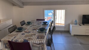 Een eetgedeelte met een tafel gedekt voor vier personen, met een tafelkleed met een patroon en stoelen.
