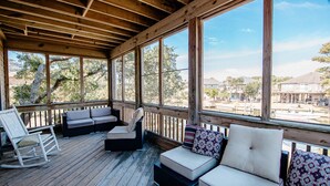 Un espace extérieur aménagé, abrité et doté d’un plancher en bois, de sièges confortables et de grandes fenêtres offrant une vue sur les environs.