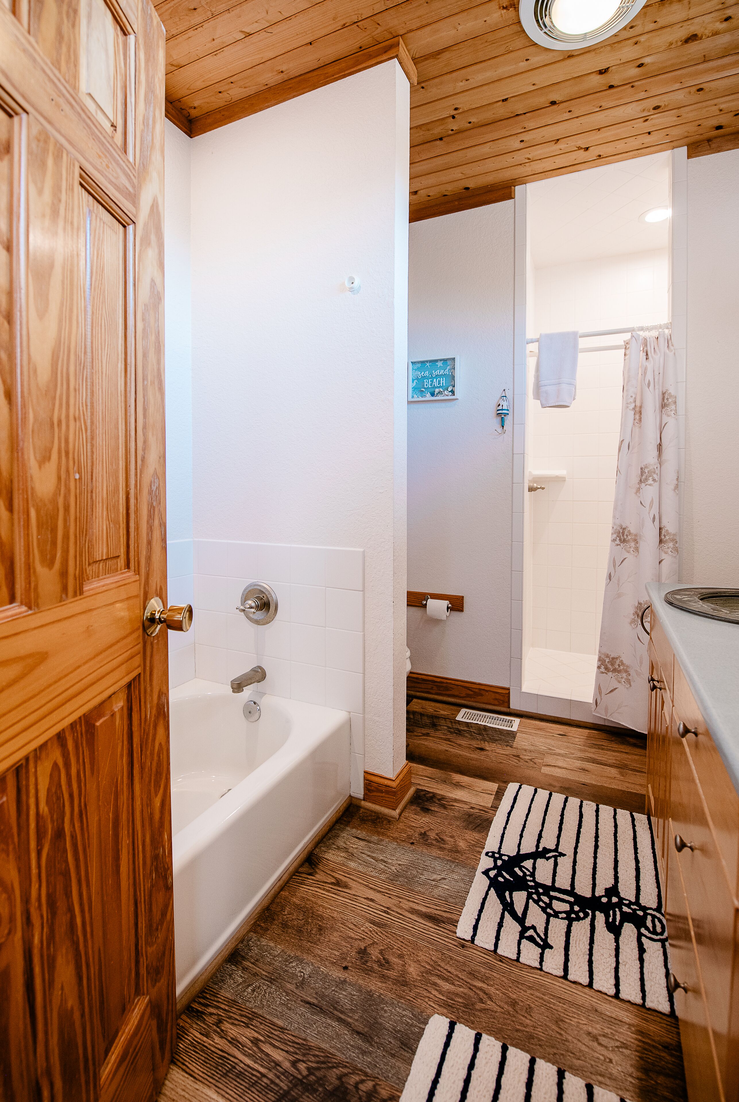 Une salle de bain avec une porte en bois, une baignoire, des toilettes et un rideau de douche.
