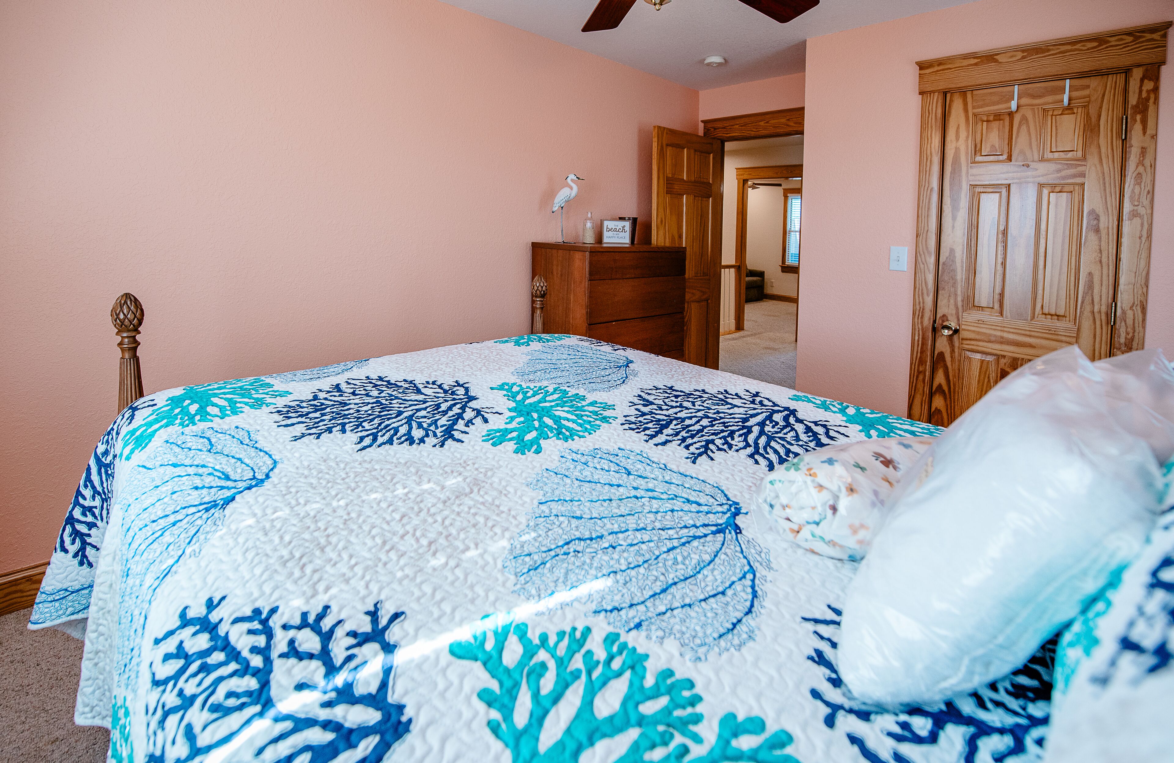Un dormitorio con cama, cómoda de madera y una puerta.