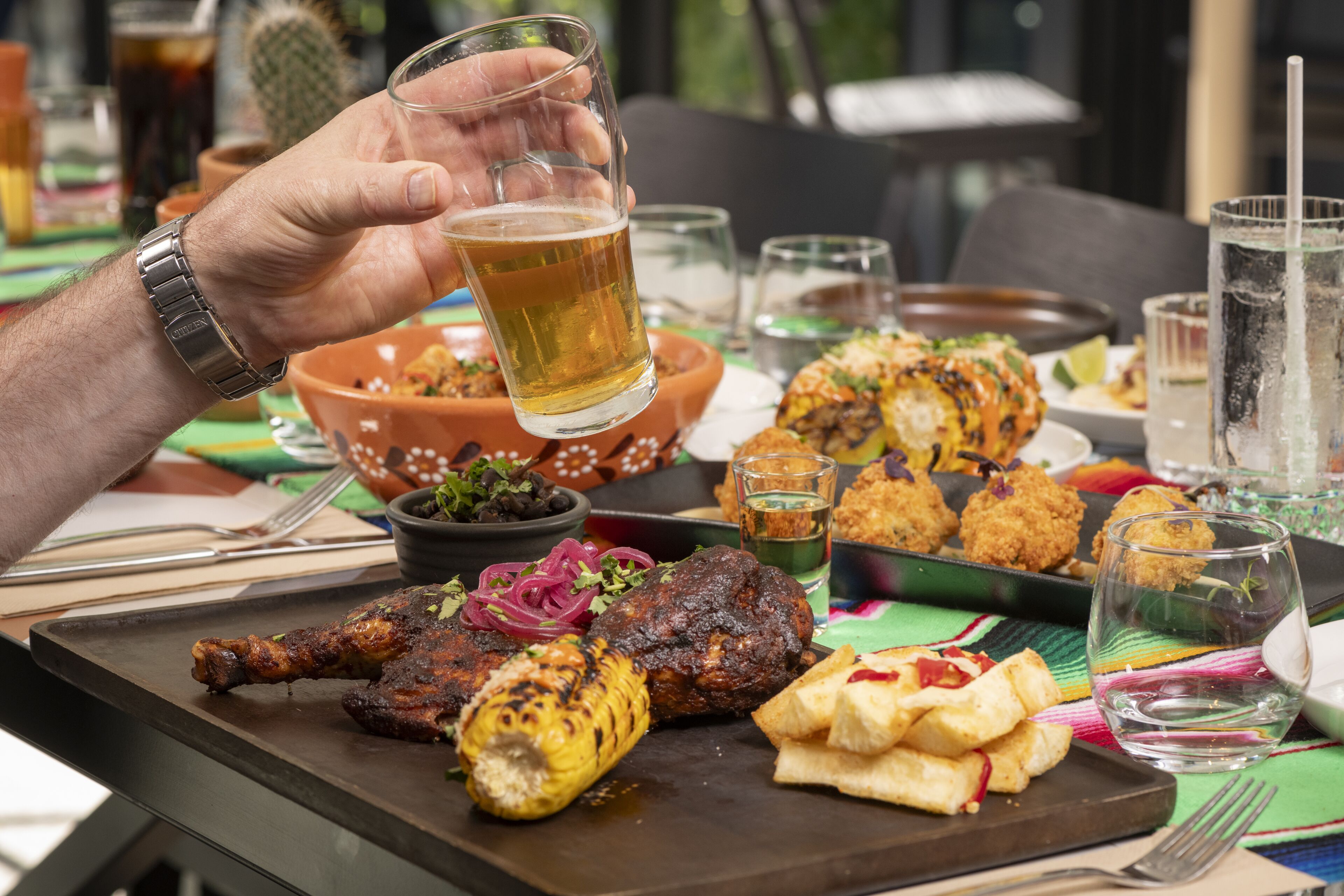 A dining table with a variety of dishes, including grilled meat, corn, and tortillas.