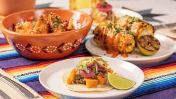 A table with a colorful woven tablecloth, a bowl of food, and a plate with a lime wedge.
