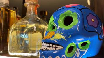 Un crâne aux couleurs vives et une bouteille de tequila Patron sont posés sur une étagère.