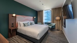 Una camera d'albergo moderna con un letto grande, una scrivania, una sedia e una TV.