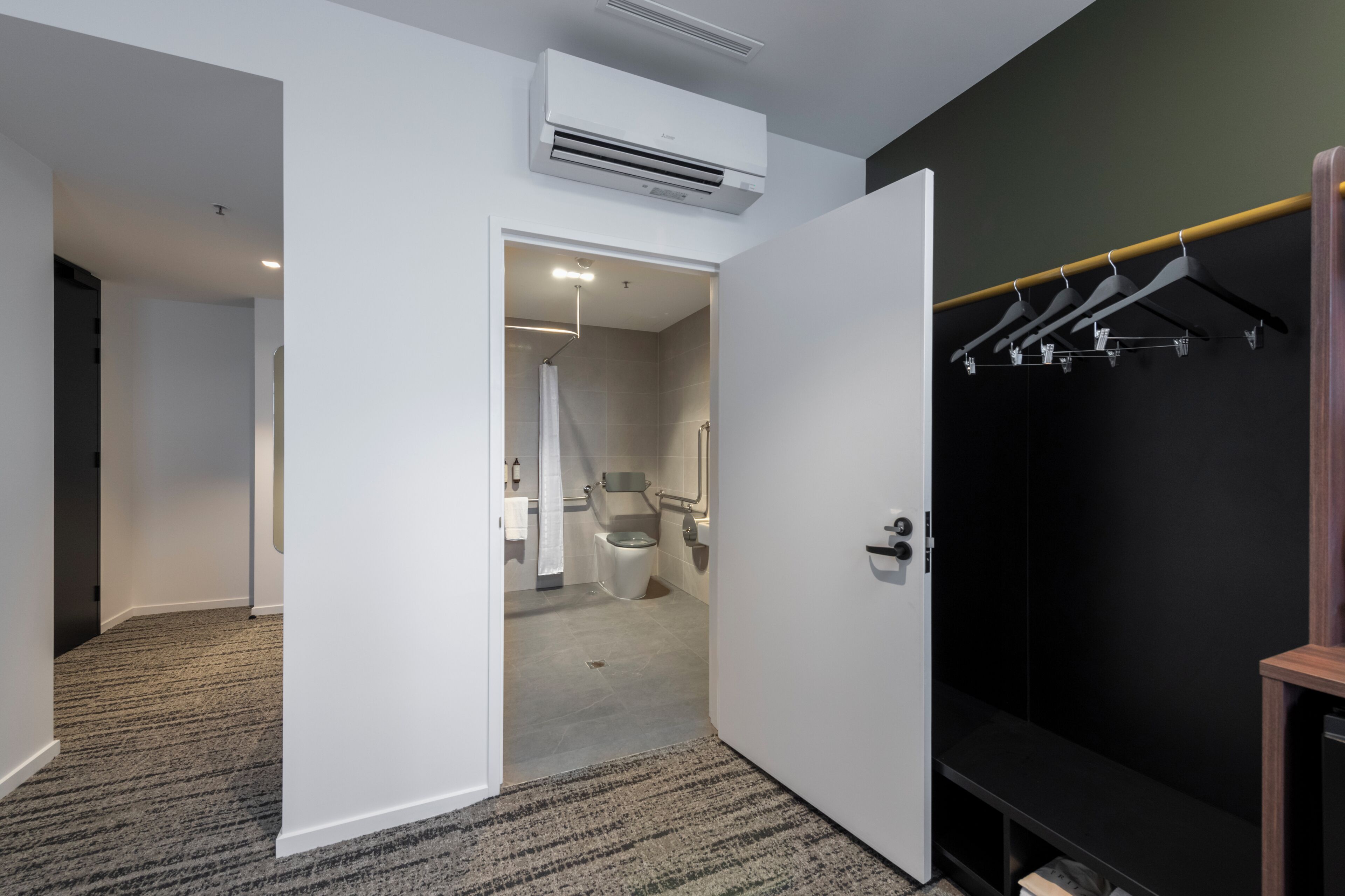 Habitación de hotel con vestidor, ducha y pasillo que conduce a otra habitación.