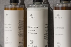 Tres botellas de productos PRIJA para el cuidado corporal: un champú, un acondicionador con extracto de nuez verde y un gel de ducha con ginseng.