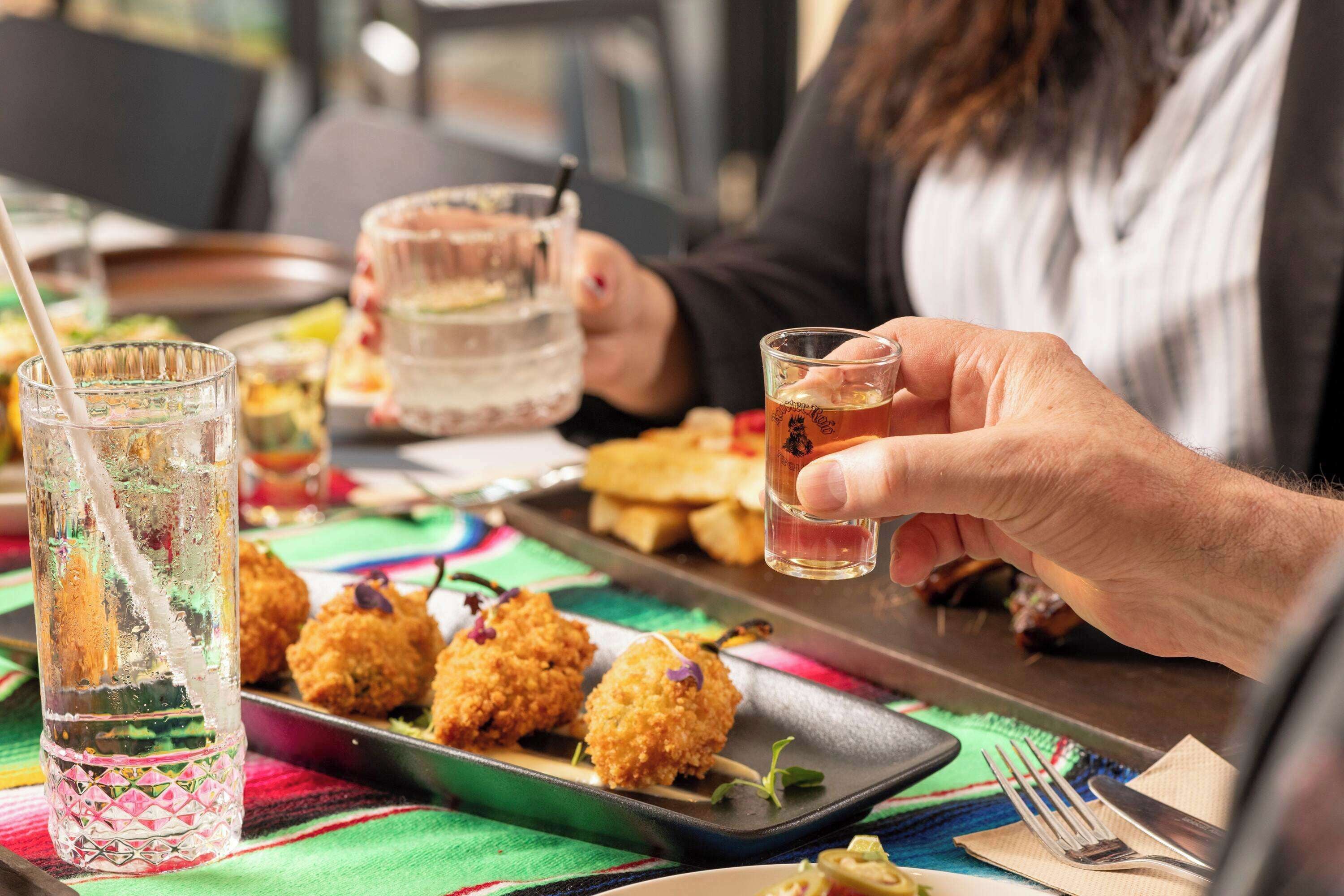 A dining table with a tray of food, a glass of water, and a glass of beer.