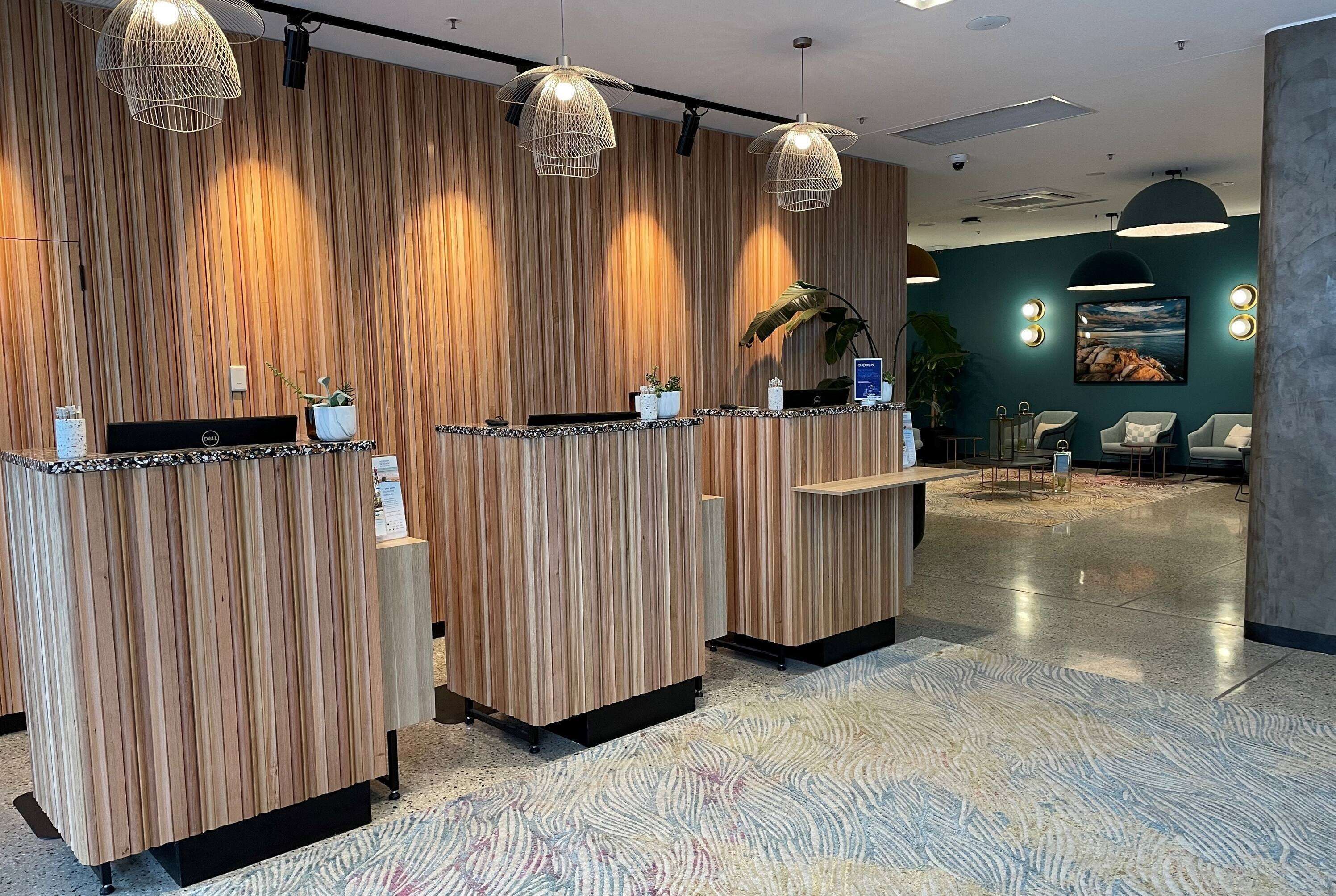 A reception area with wooden panel walls, a reception desk, and a seating area with chairs and a plant.