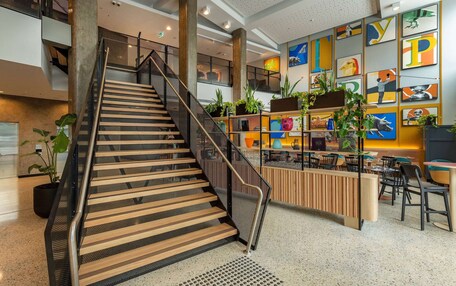 A modern interior with a staircase, seating area, and artwork on the walls.